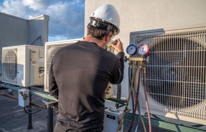 Professional HVAC contractor inspecting a residential heating and cooling system during a routine maintenance visit.